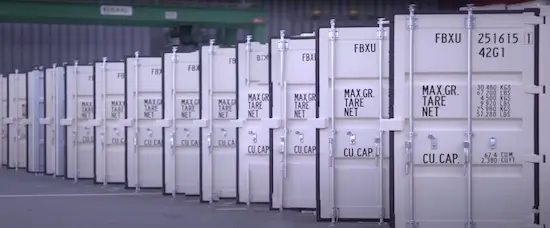 A long, uniform row of white 40ft high cube shipping containers displaying CSC plates and ID codes, symbolizing large inventory availability.