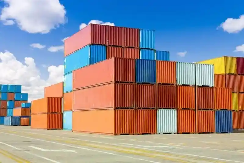 Colorful stacks of red, orange, blue, and yellow shipping containers under a bright blue sky, symbolizing vast inventory.