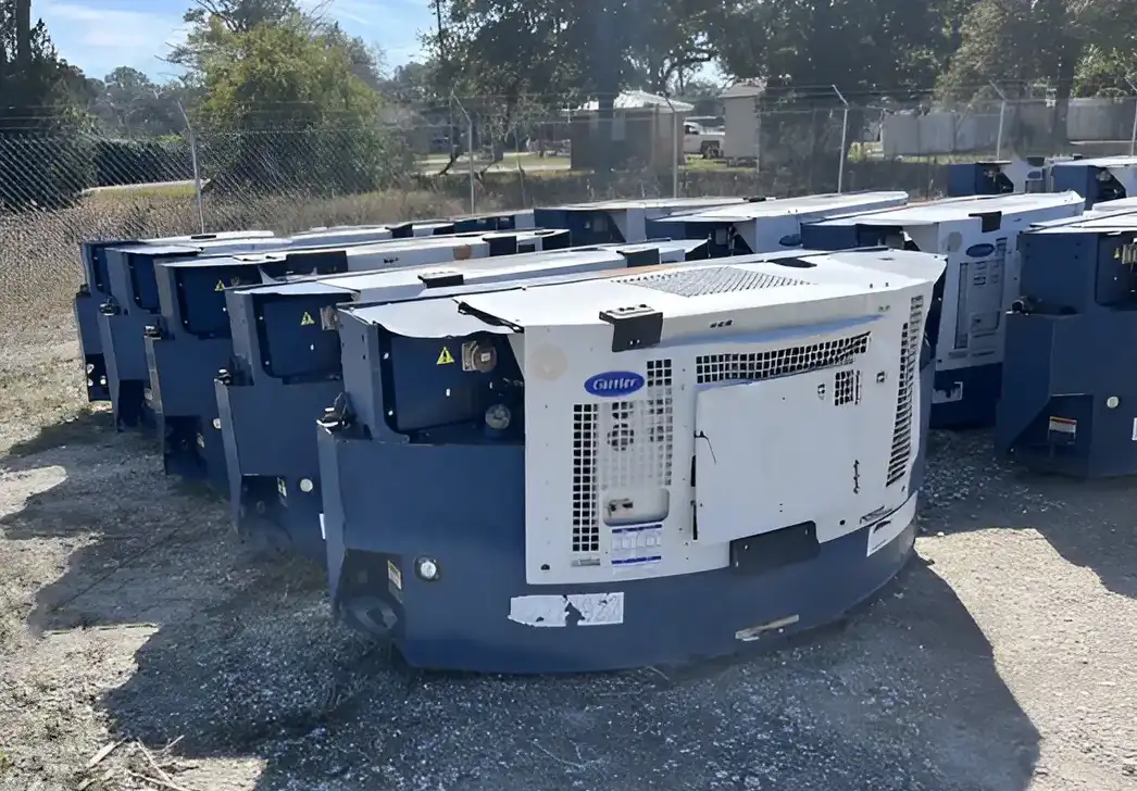 Used clip-on Carrier refrigeration units are stacked in an outdoor storage area, ready for use with refrigerated containers or trailers