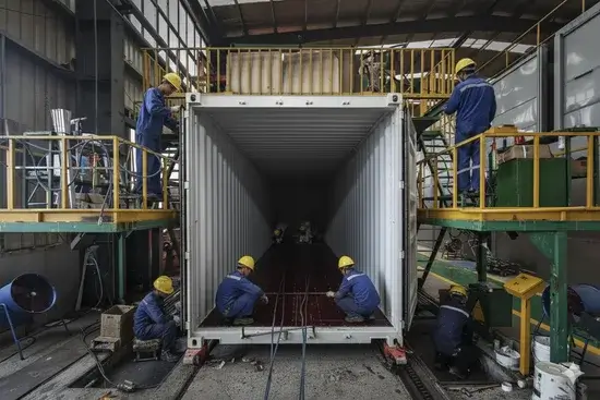 A row of newly manufactured red shipping containers on a factory floor, showcasing the quality and readiness for delivery.