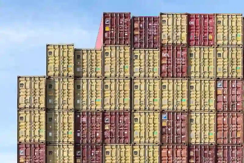 Uniform stacks of red and yellow shipping containers, emphasizing the quantity, durability, and standardization of the global fleet.